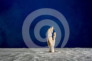 Wooden hand gesticulating against a blue background