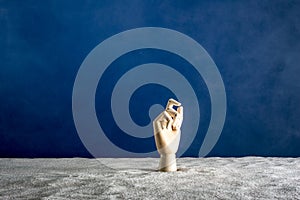 Wooden hand gesticulating against a blue background