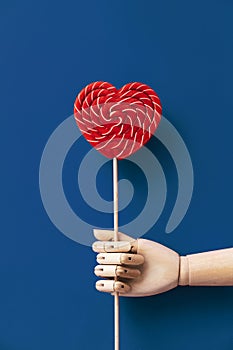 Wooden hand holding a large blue and white striped lollipop