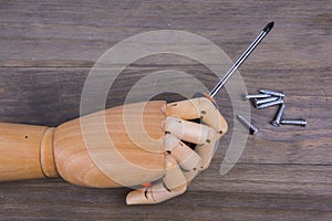 Wooden hand holding a phillips screwdriver