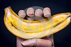 Wooden hand holding a split banana in half