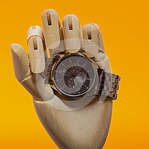 Wooden Hand with modern chronograph watch on an orange background