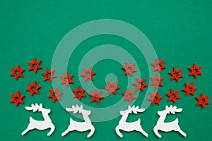 Wooden handmade Christmas decorations white Deers and red Stars with a pattern on a green isolated background. Flat lay, top view
