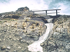 Wooden handrail and sign on trekking path at Dolomites mountains