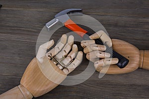 Wooden hands holding hammers and nails
