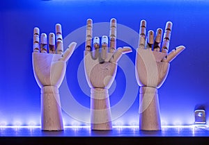 Wooden hands made of beech imitating the gesture of a rocker goat on a shelf with blue illumination. Rock symbol, hand gesture