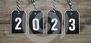 Wooden hang tag and slate with four leaf clover and sparklers with the german words for happy new year - frohes neues jahr 2023 on