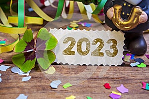 Wooden hang tag and slate with four leaf clover and sparklers with the german words for happy new year - frohes neues jahr 2023 on