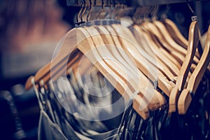 Wooden hangers with clothes on the rail in the store. Shopping in store. Clothes on hangers in shop for sale