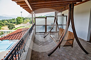 Wooden hanging bench for relaxation on the house balcony