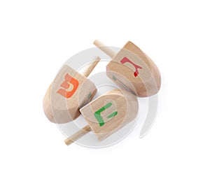 Wooden Hanukkah traditional dreidels with letters Gimel, Pe and He on white background, top view