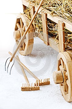 Wooden hay cart on a white background. Forks and rakes