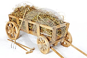 Wooden hay cart on a white background. Forks and rakes