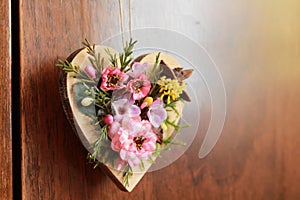 Wooden heart adorned with artificial colorful flowers hanging on the closet door