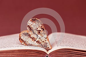 A wooden heart with bark on an old book