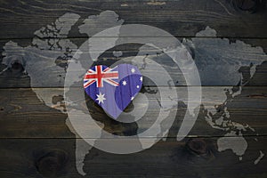 wooden heart with national flag of australia near world map on the wooden background