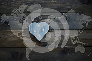 wooden heart with national flag of Federated States of Micronesia near world map on the wooden background