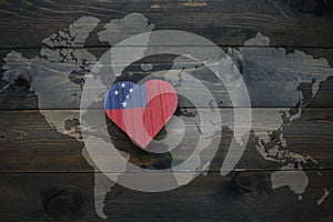 wooden heart with national flag of Samoa near world map on the wooden background