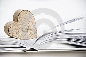 Wooden heart shape on a open book. Love reading concept close up.