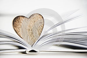 Wooden heart shape on a open book. Love reading concept close up.