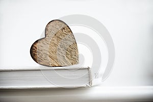 Wooden heart shape on a open book. Love reading concept close up.