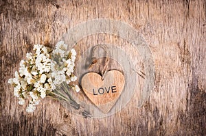 Wooden heart and white flowers on an old wooden board. Backgrounds and textures. St. Valentine`s Day.