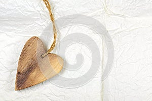 Wooden heart on white handmade crumple paper. Valentine Day.