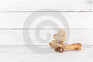 Wooden Heart on Wooden Toy Plane over white wood background.  Fly to love concept with copy space