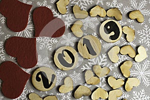 Wooden hearts, red textile hearts and wooden elements with number 2019 on snowflake background. New Year concept.