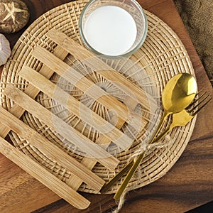 Wooden heating pad with a glass of milk and spoon and fork with blank text space