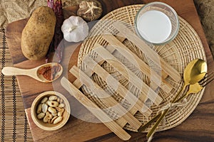 Wooden heating pad with a glass of milk and spoon and fork with blank text space