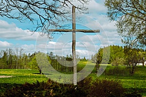 Wooden High Cross with blue sky and a few white clouds above a green landscape