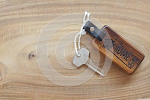 Wooden home keyring with house skeleton key on light wooden floor. Welcome to new home concept. Copy space