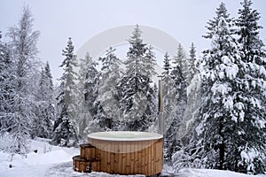 Wooden hot tub near a winter forest on a snowy day, Kroderen, Norway