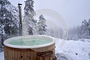 Wooden hot tub near a winter forest on a snowy day, Kroderen, Norway