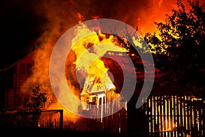 Wooden house or barn burning on fire at night