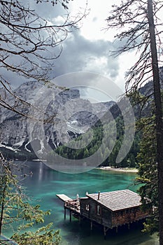 Wooden house, big mountains and blue lake in Lago di Braies, Dolomites Alps, Italy