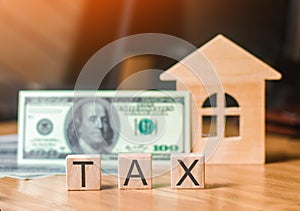 Wooden house and a bill of one hundred dollars, inscription taxes. Concept of property taxes, purchase and sale of property.