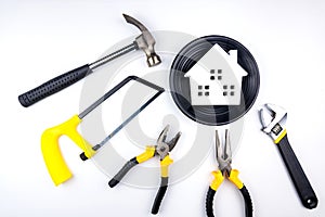 Wooden house in black dish and construction tools on isolated on white background with copy space.Home Repair concept, Repair