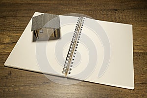 Wooden house on blank white notebook
