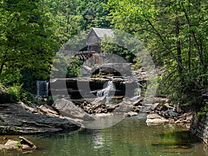 Wooden house with a cascading stream running through a lush green forest in Babcock State Park