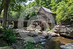 Wooden house with a cascading stream running through a lush green forest in Babcock State Park