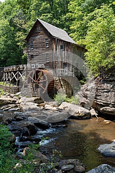Wooden house with a cascading stream running through a lush green forest in Babcock State Park