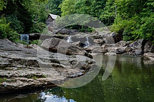 Wooden house with a cascading stream running through a lush green forest in Babcock State Park