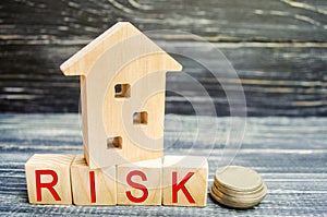 Wooden house and cubes with the word `risk`. The concept of risk, loss of real estate. Property insurance. Loans secured by home,