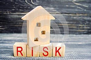 Wooden house and cubes with the word `risk`. The concept of risk, loss of real estate. Property insurance. Loans secured by home,