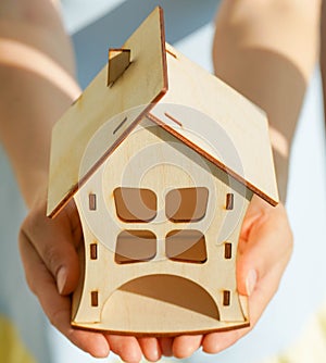 Wooden house in female hands as a symbol. Stay home to reduce the risk of infection and spread of the virus