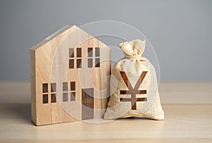 Wooden house figure and chinese yuan or japanese yen money bag.