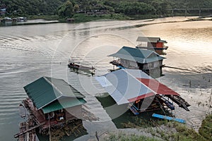 Wooden house floating on dam with fishing boat