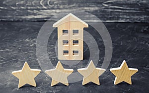 Wooden house and four stars on a gray background. Rating of houses and private property. Buying and selling, renting apartments.